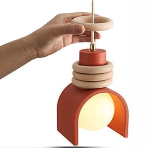 Modern terracotta-colored arch pendant light with wooden ring accents and a glowing globe bulb.
