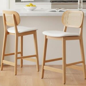 Set of two modern light wood bar stools with cane rattan backs and white upholstered seats.