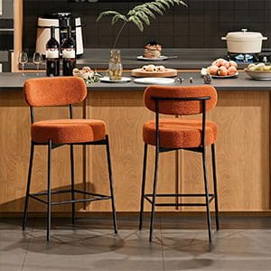 Two modern burnt orange upholstered bar stools with black metal legs at a wooden kitchen island.