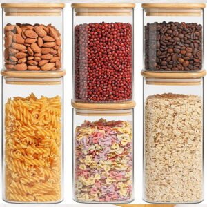 Set of airtight glass kitchen canisters with bamboo lids, filled with pasta, nuts, and grains for pantry organization.