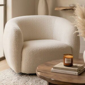 Round white textured boucle armchair in a living room near a wooden coffee table with books.