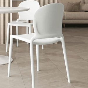 Modern white molded plastic dining chair with sleek legs in a bright, contemporary interior.