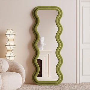 Large floor-standing wavy full-length mirror with a vibrant olive green frame in a minimalist room.