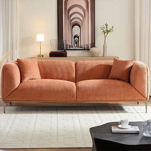 Modern terracotta-colored fabric sofa with sleek metal legs in a bright living room with arched wall art