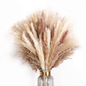 Large fluffy pampas grass bouquet in natural beige and soft pink tones in a fluted glass vase with a gold rim.