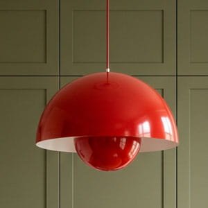 Iconic red Flowerpot-style pendant light with a glossy dome finish against a sage green wall.